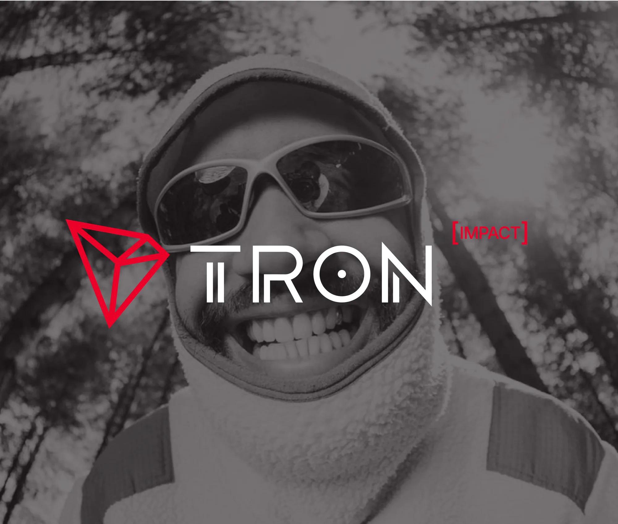 The TRON IMPACT logo over a desaturated, wide-angle portrait of a smiling man in ski goggles.